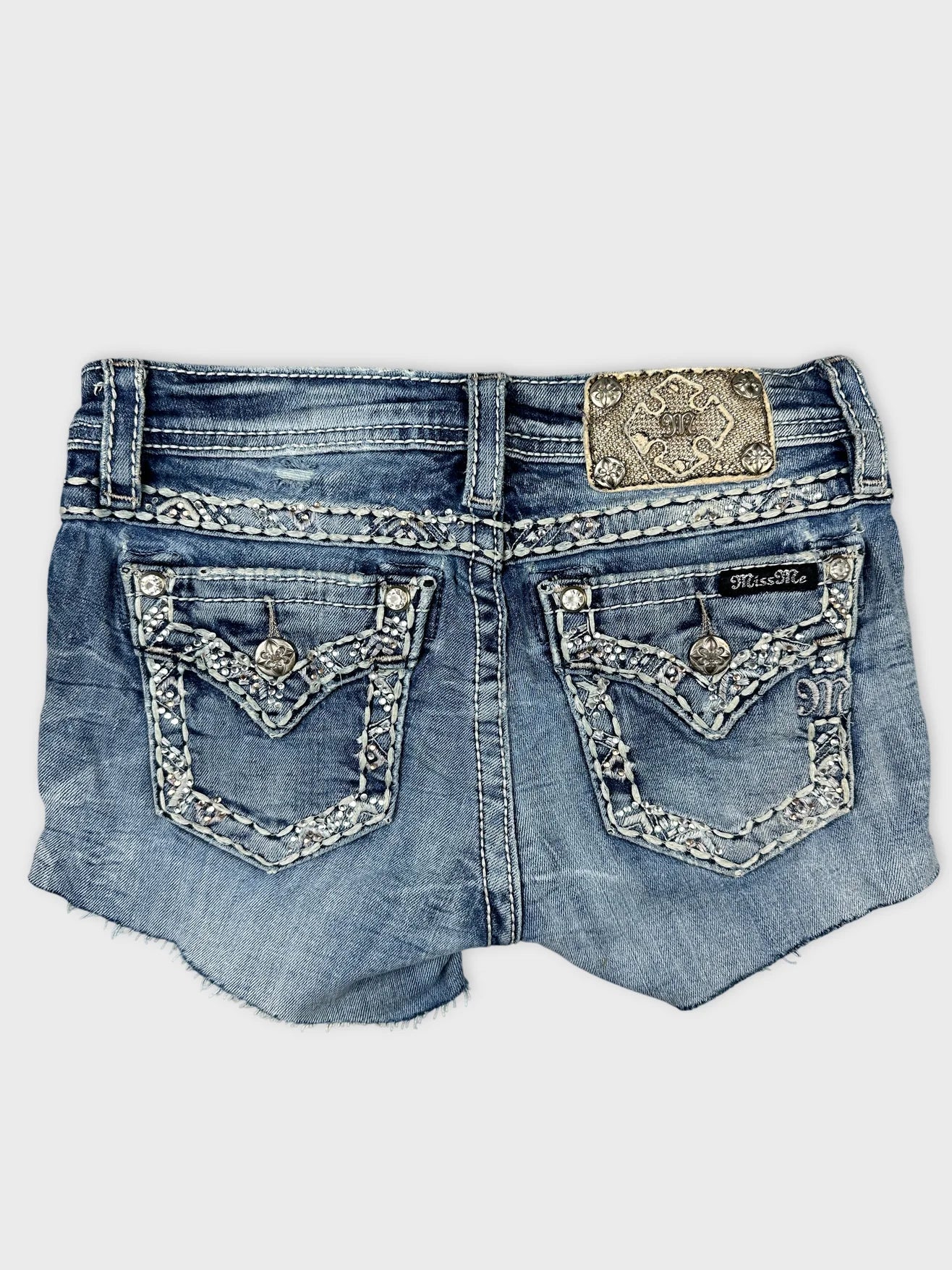Back view of denim shorts in blue with embellished pockets.
