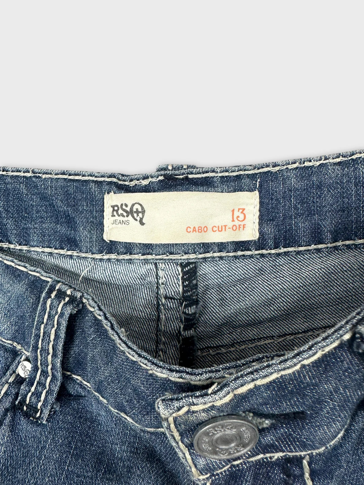 Detail view of denim shorts with a dark wash and visible stitching.