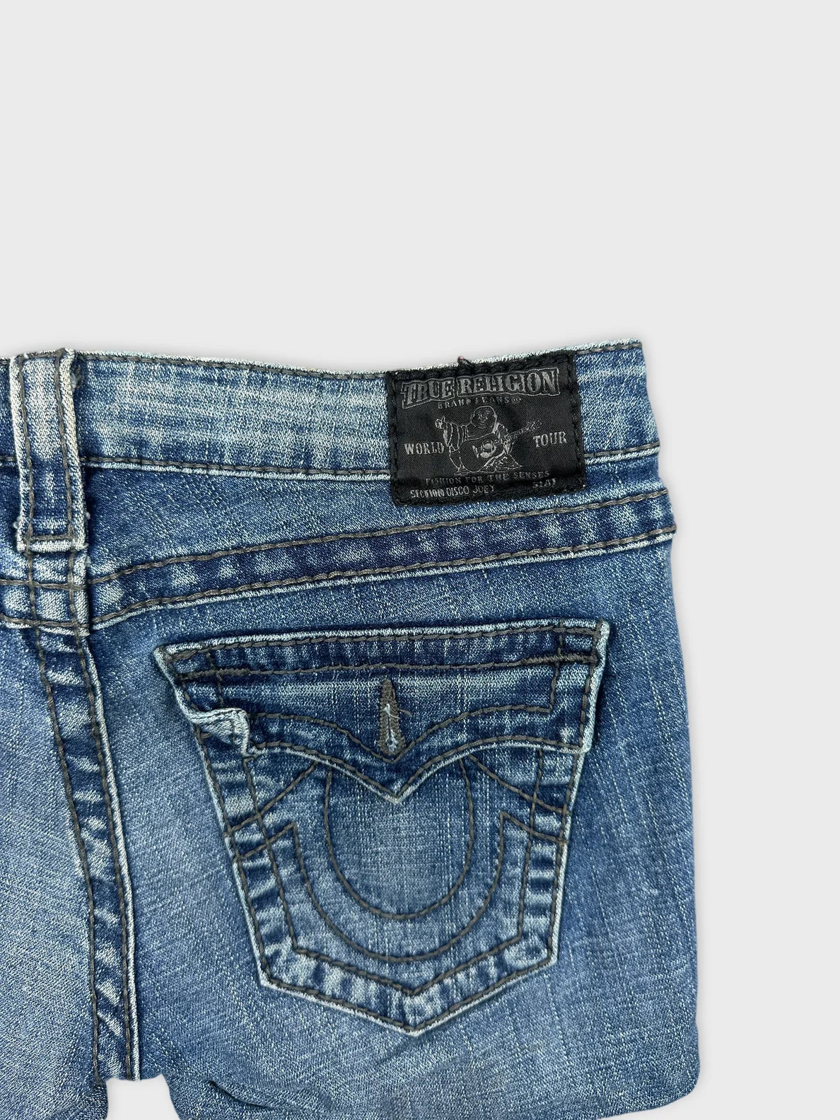 Detail view of blue denim shorts featuring decorative back pocket stitching.