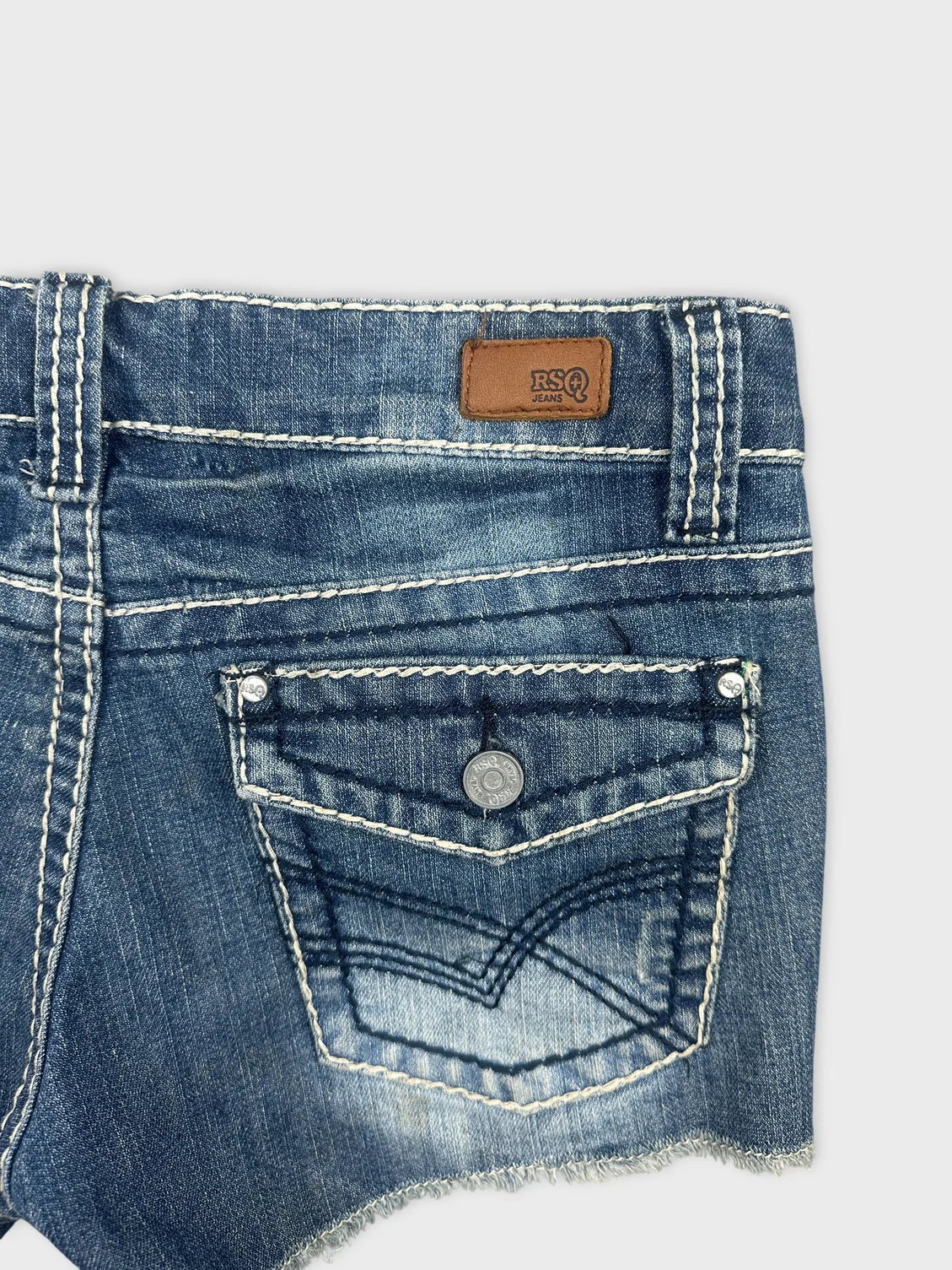 Detail view of denim shorts in dark blue with back pocket design.