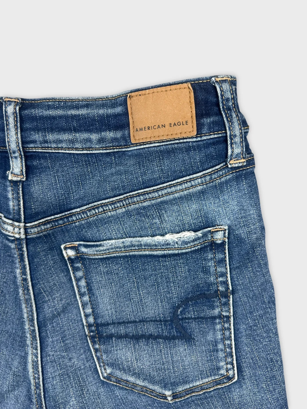 Detail view of blue denim shorts featuring a pocket and brand tag.