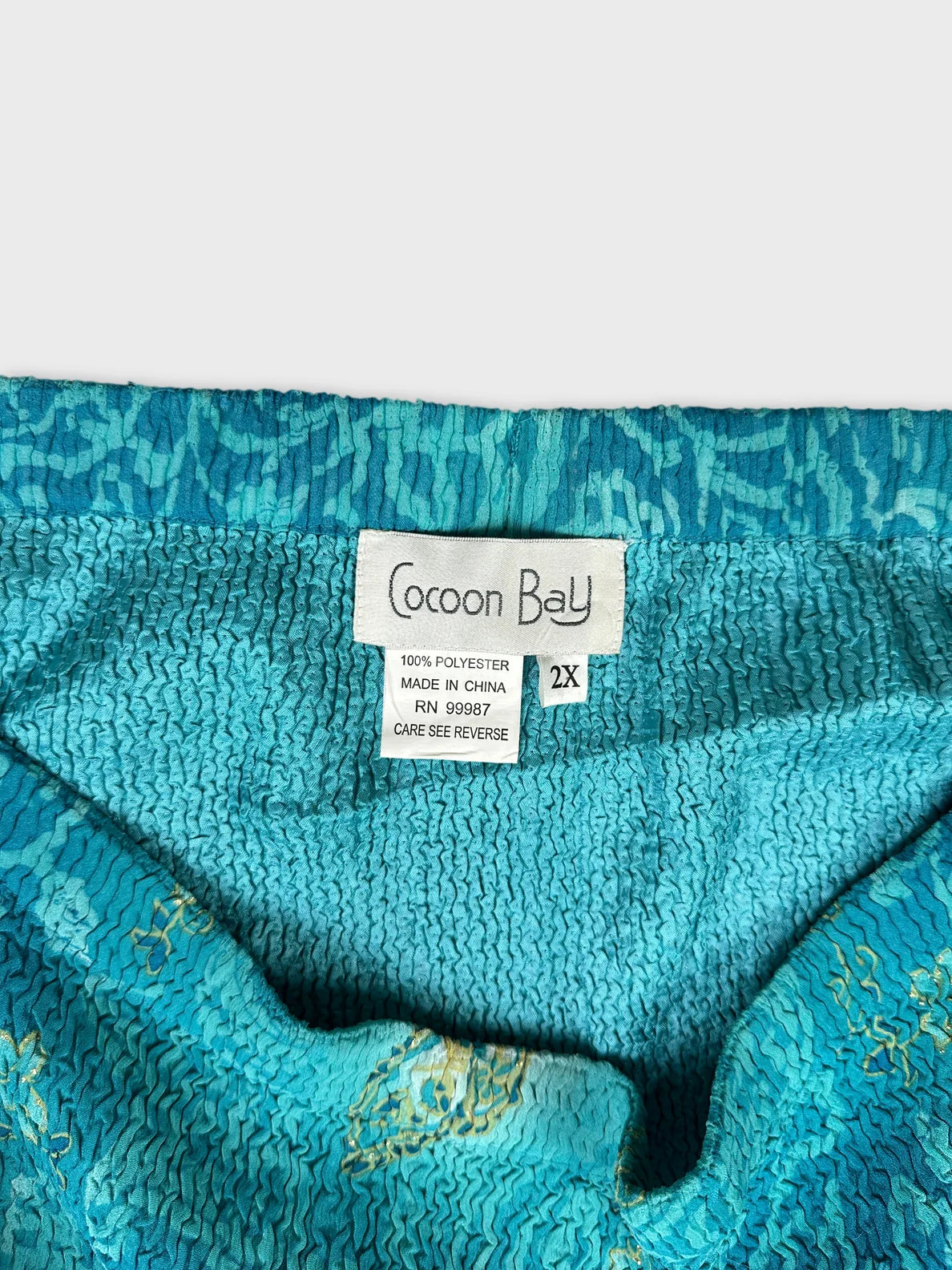 Detail view of a turquoise women's dress featuring textured fabric.