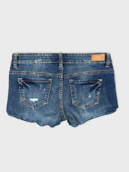Back view of blue denim shorts featuring distressed details and two back pockets.