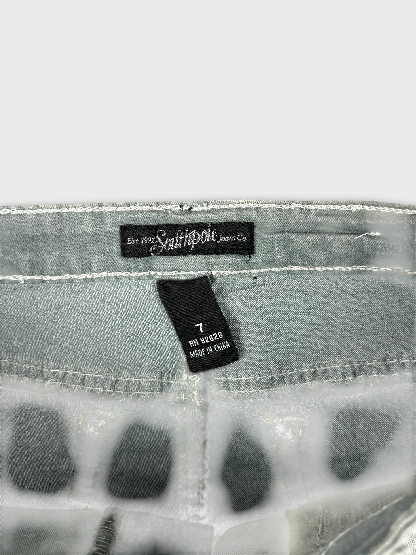 Detail view of women's jean shorts with light green fabric and unique dot pattern.