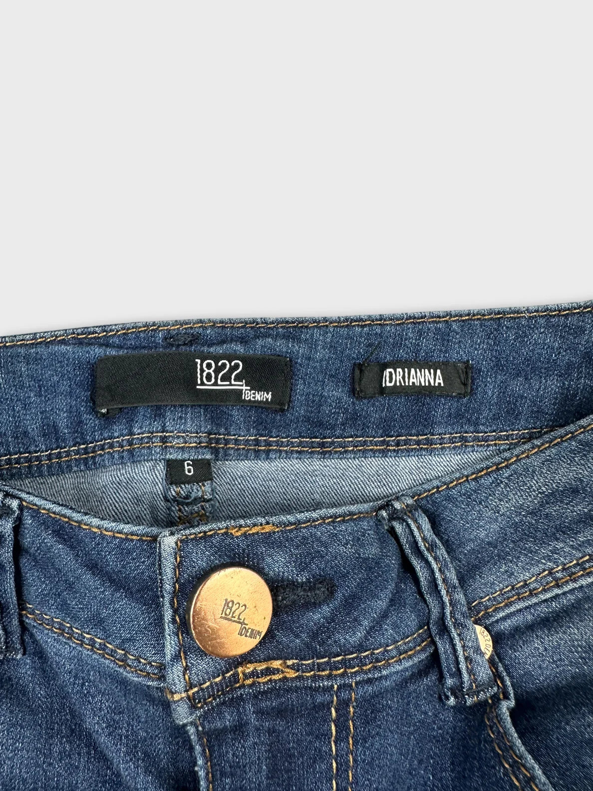 Detail view of blue denim shorts featuring a metal button closure.
