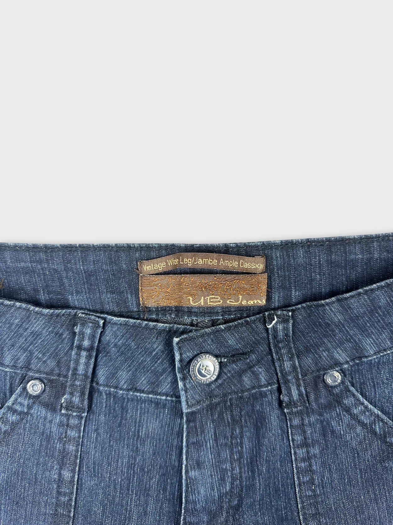 Detail view of vintage women’s denim shorts with dark blue color and button closure.