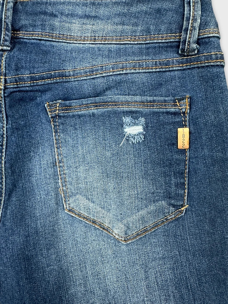 Detail view of blue denim shorts featuring a ripped pocket design and contrasting stitching.