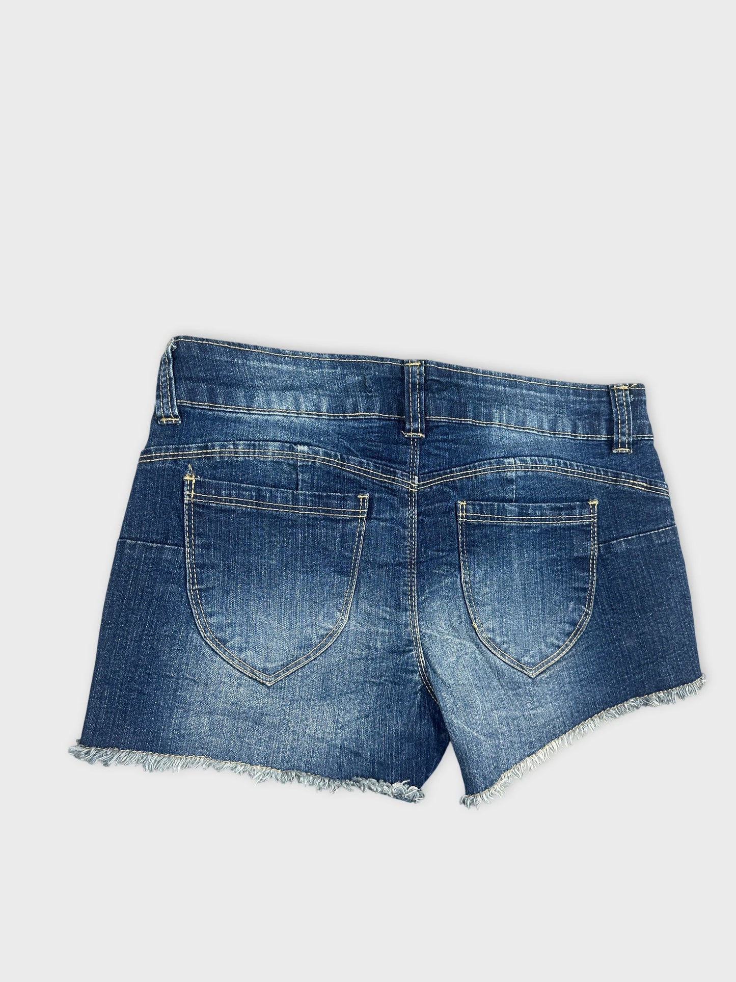 Detail view of blue denim shorts with frayed hem and back pockets.
