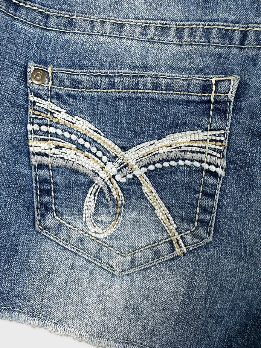 Detail view of blue denim shorts with embroidered pocket design.