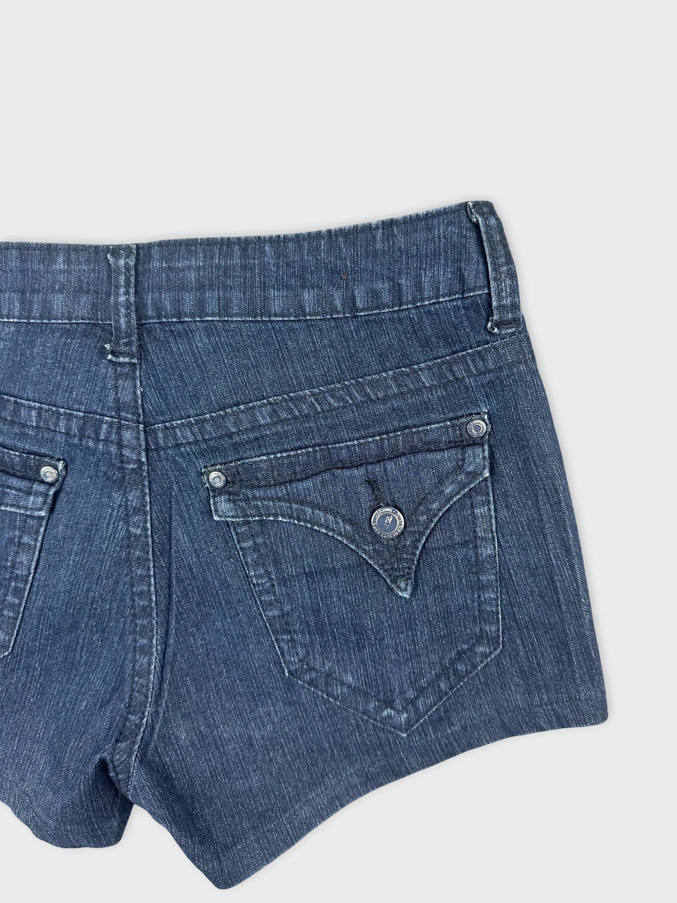 Detail view of blue denim shorts featuring back pockets with decorative stitching.