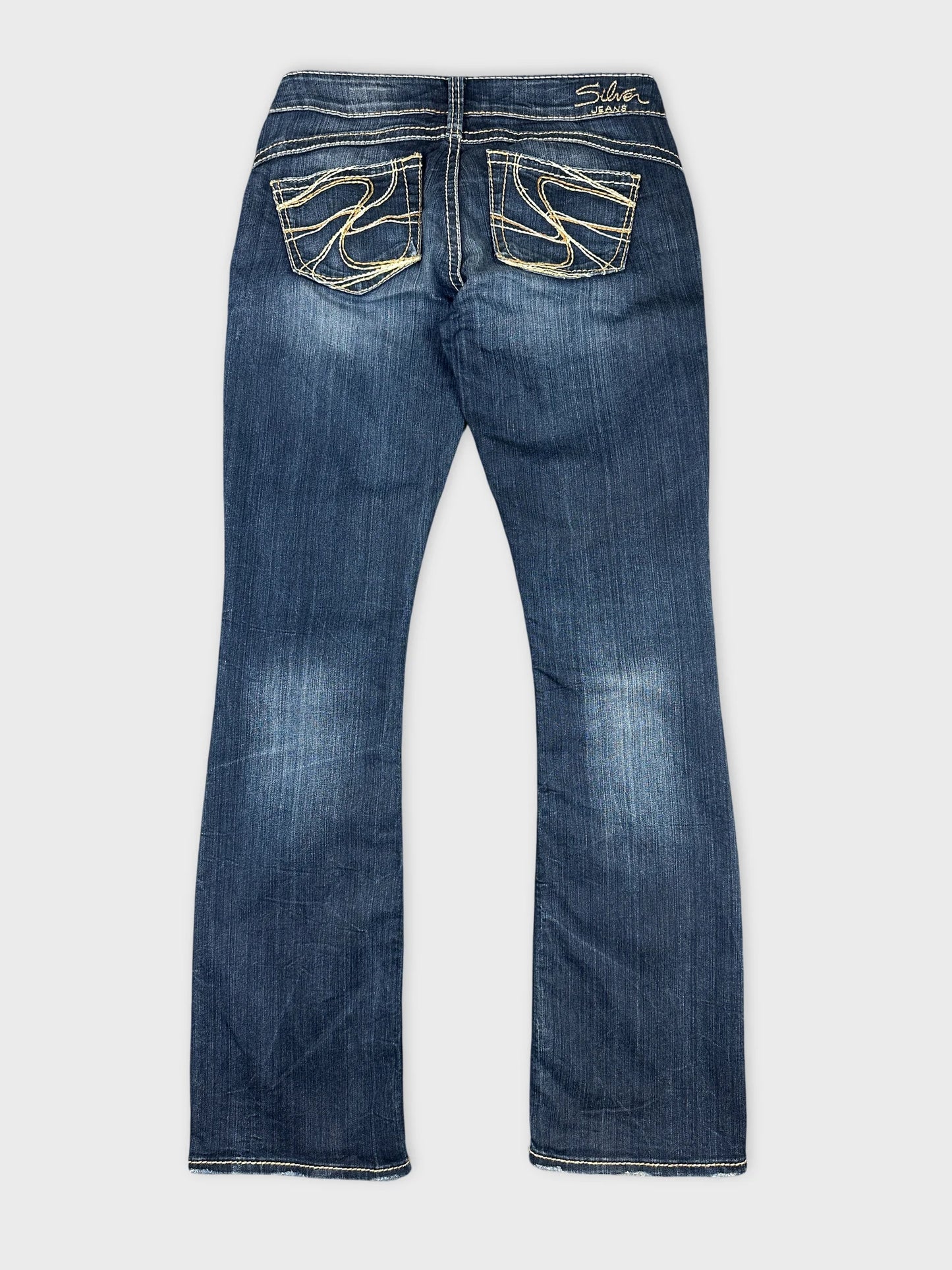 Detail view of blue jeans featuring decorative back pocket stitching.