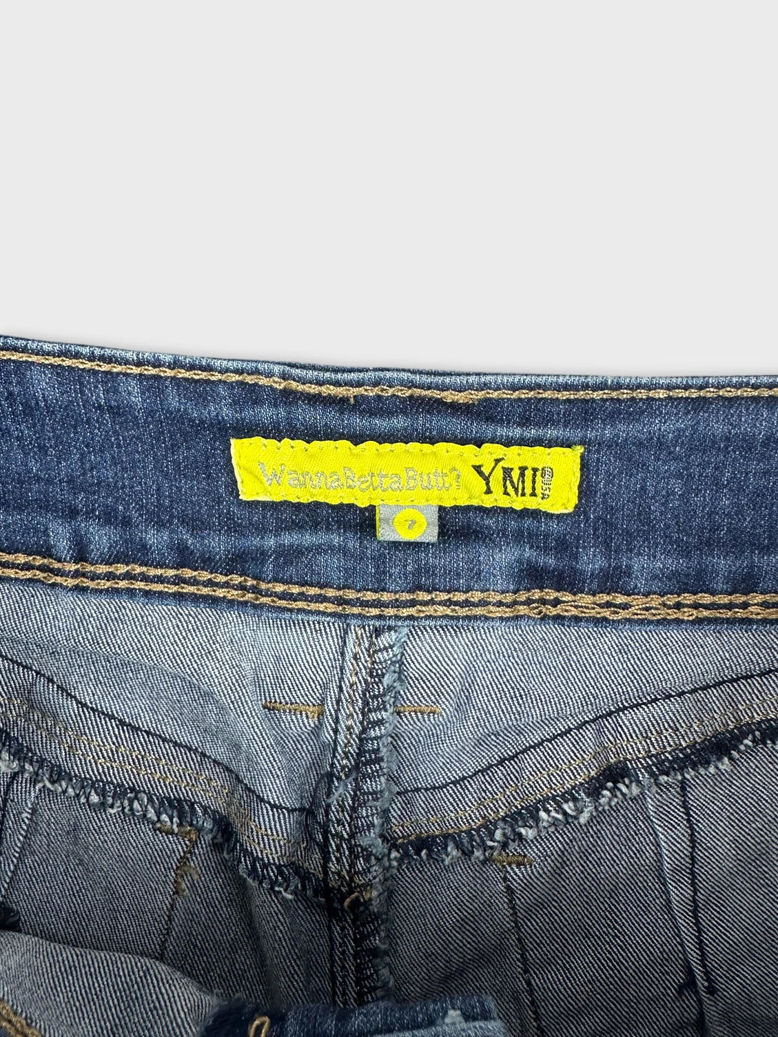 Detail view of denim mini shorts featuring frayed edges and yellow label.