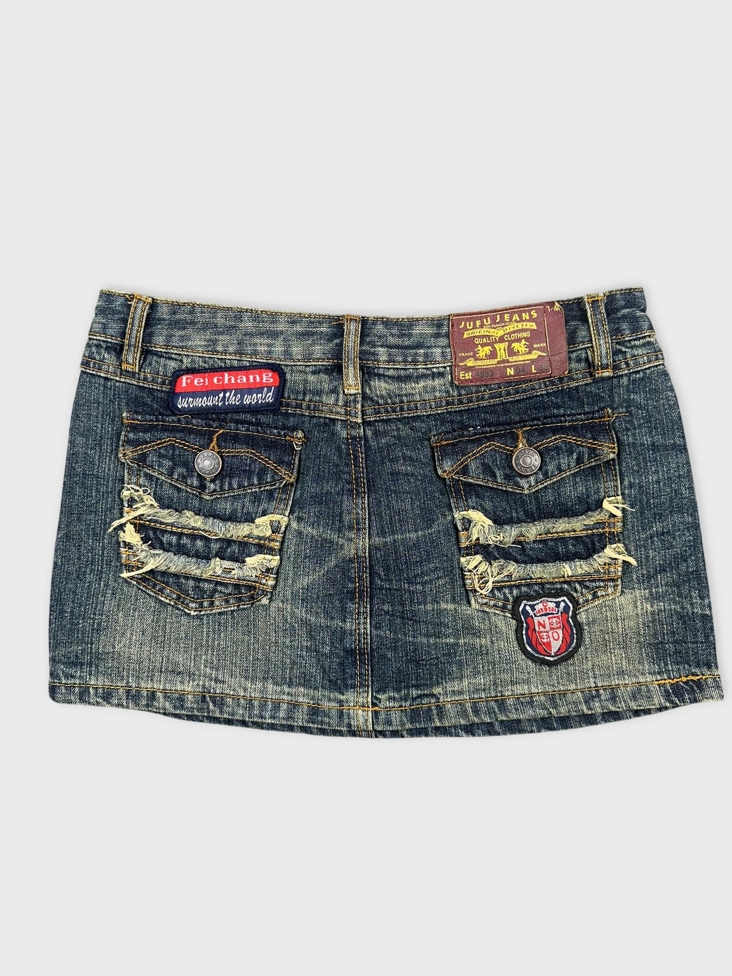 Back view of a denim mini skirt featuring distressed pockets and embroidery.
