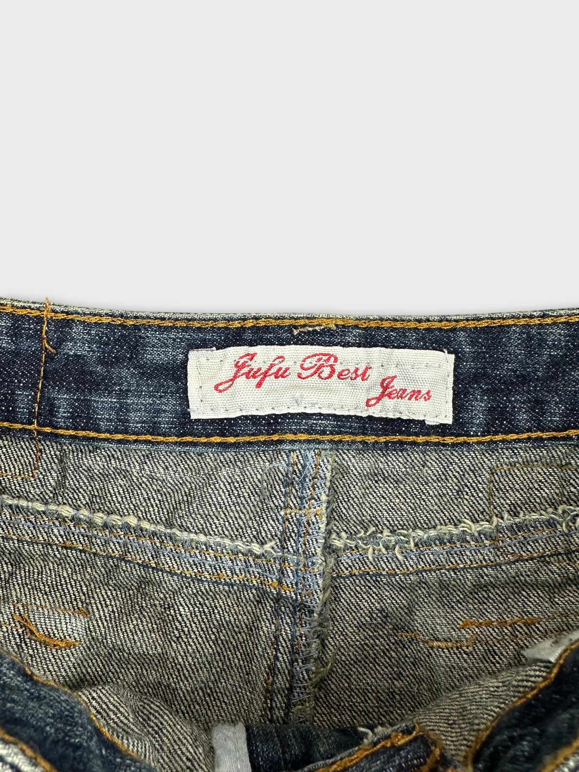 Detail view of a blue denim mini skirt with tan stitching.