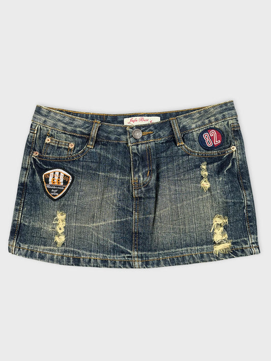 Front view of a mini denim skirt featuring patches and distressed details.
