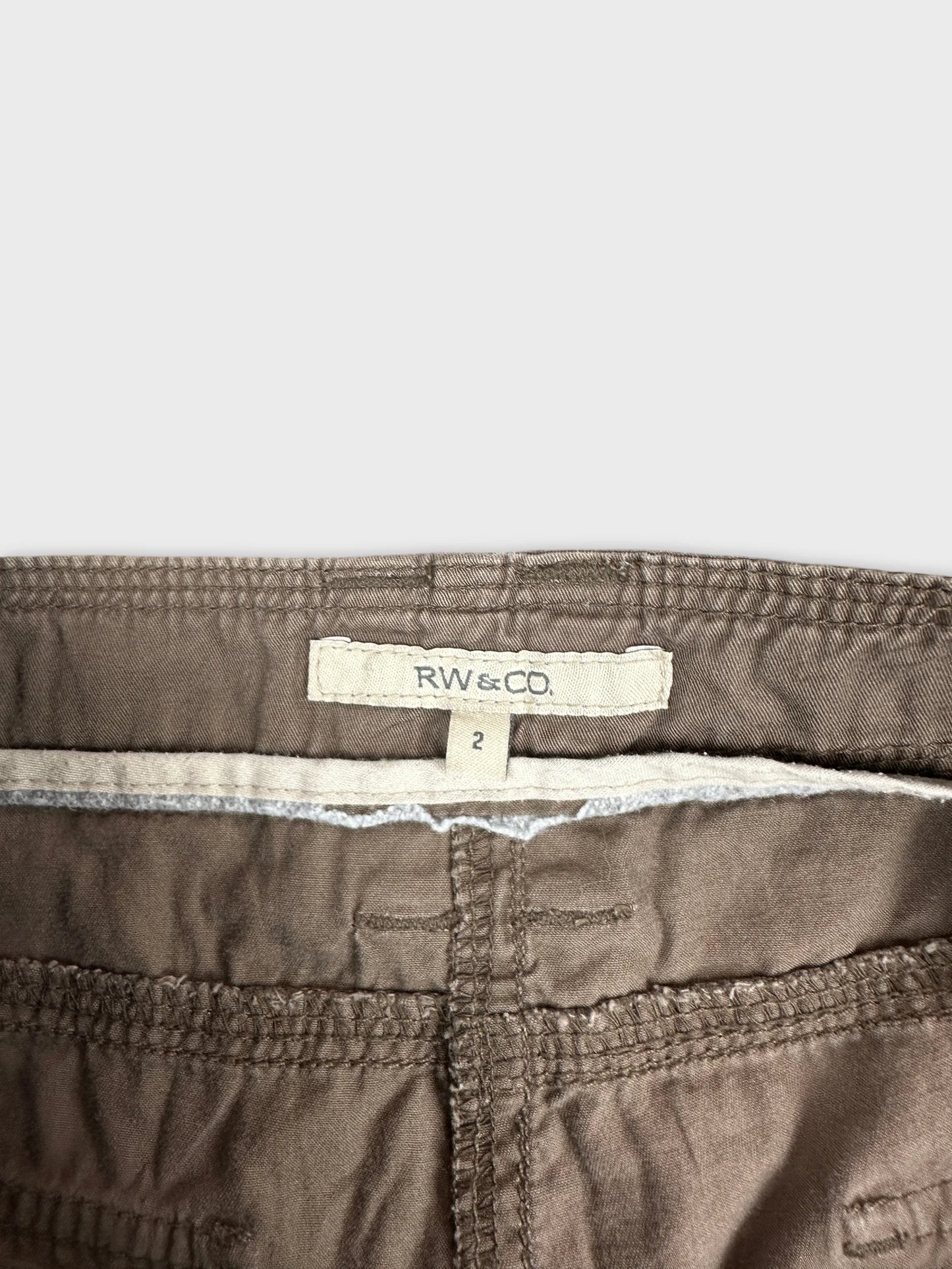 Detail view of brown cargo shorts featuring a waistband and stitching details.