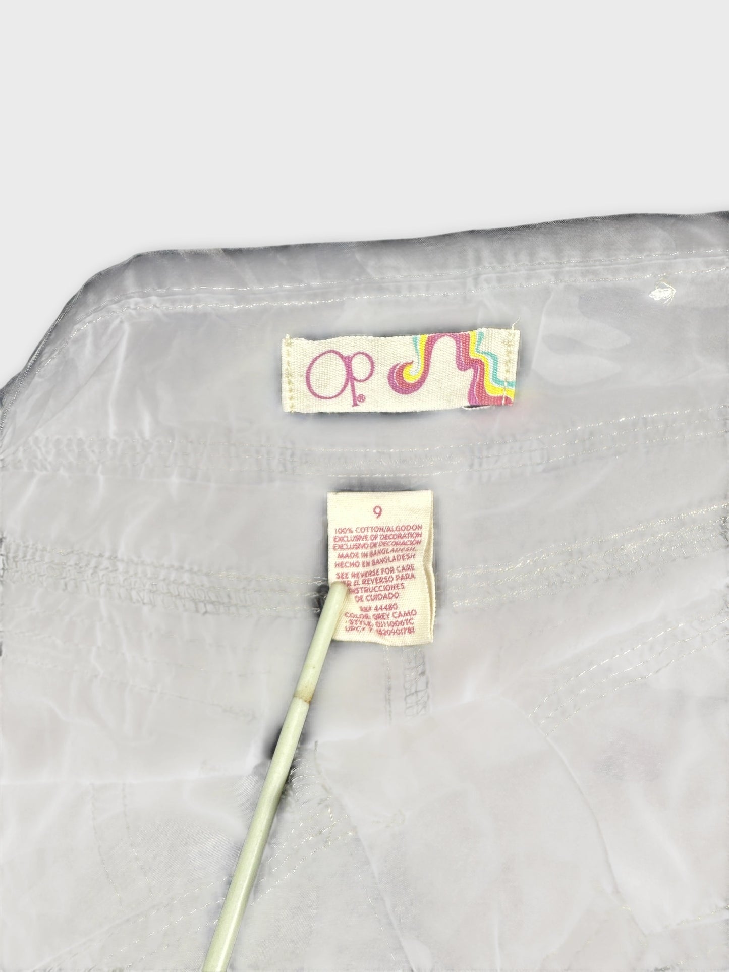 Detail view of white women shorts with a colorful label and stitching.