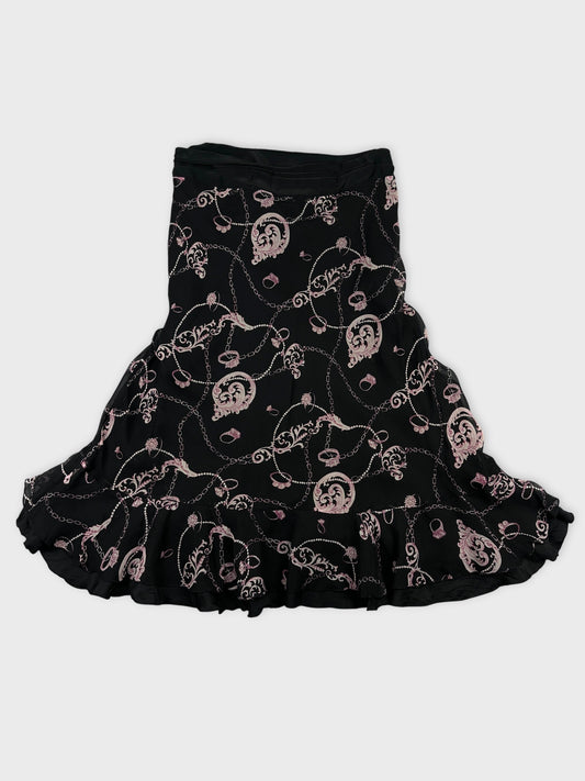 Back view of a black skirt featuring pink floral chain patterns and ruffled hem.