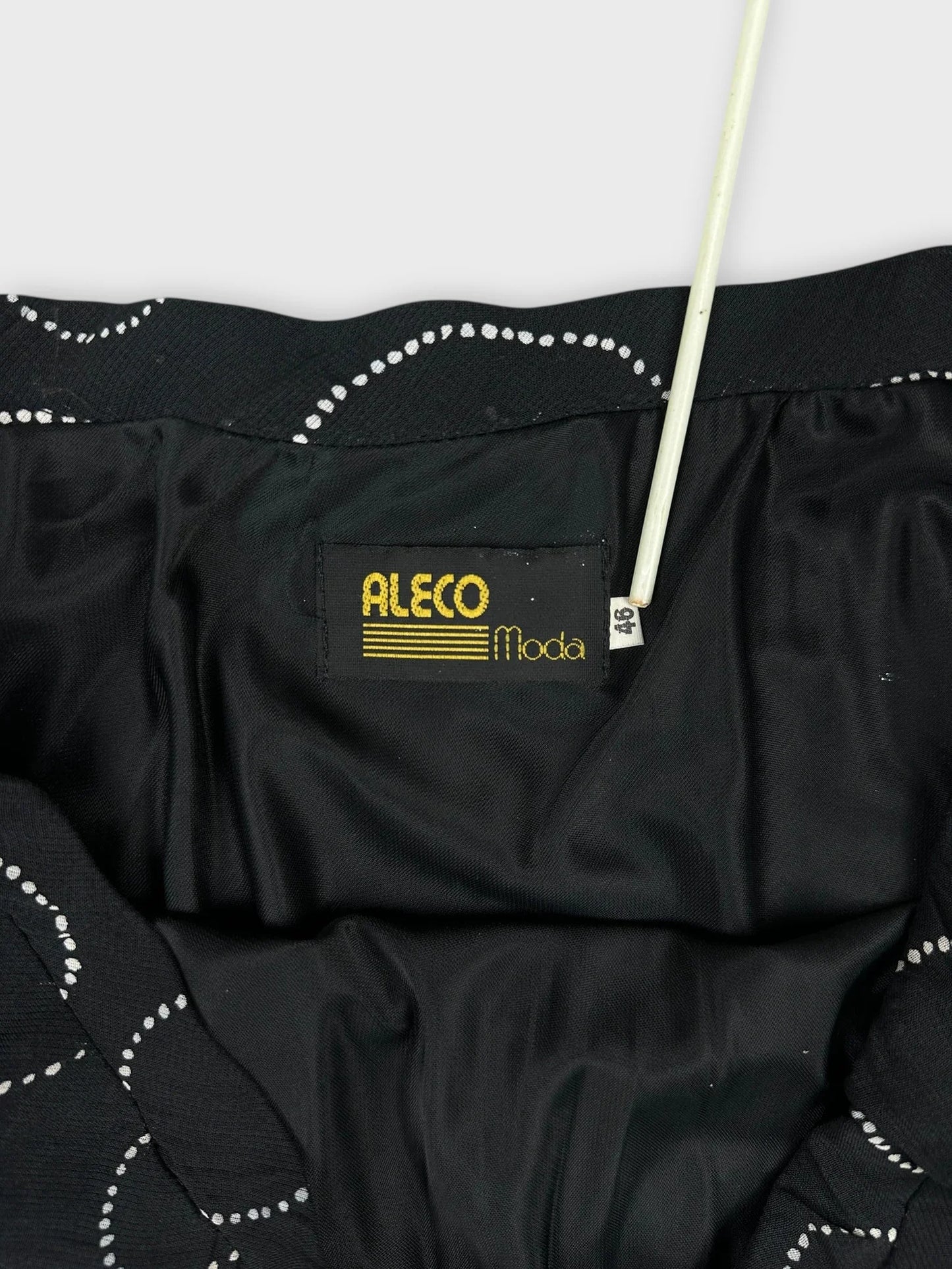 Detail view of black skirt with dotted white pattern and internal label.