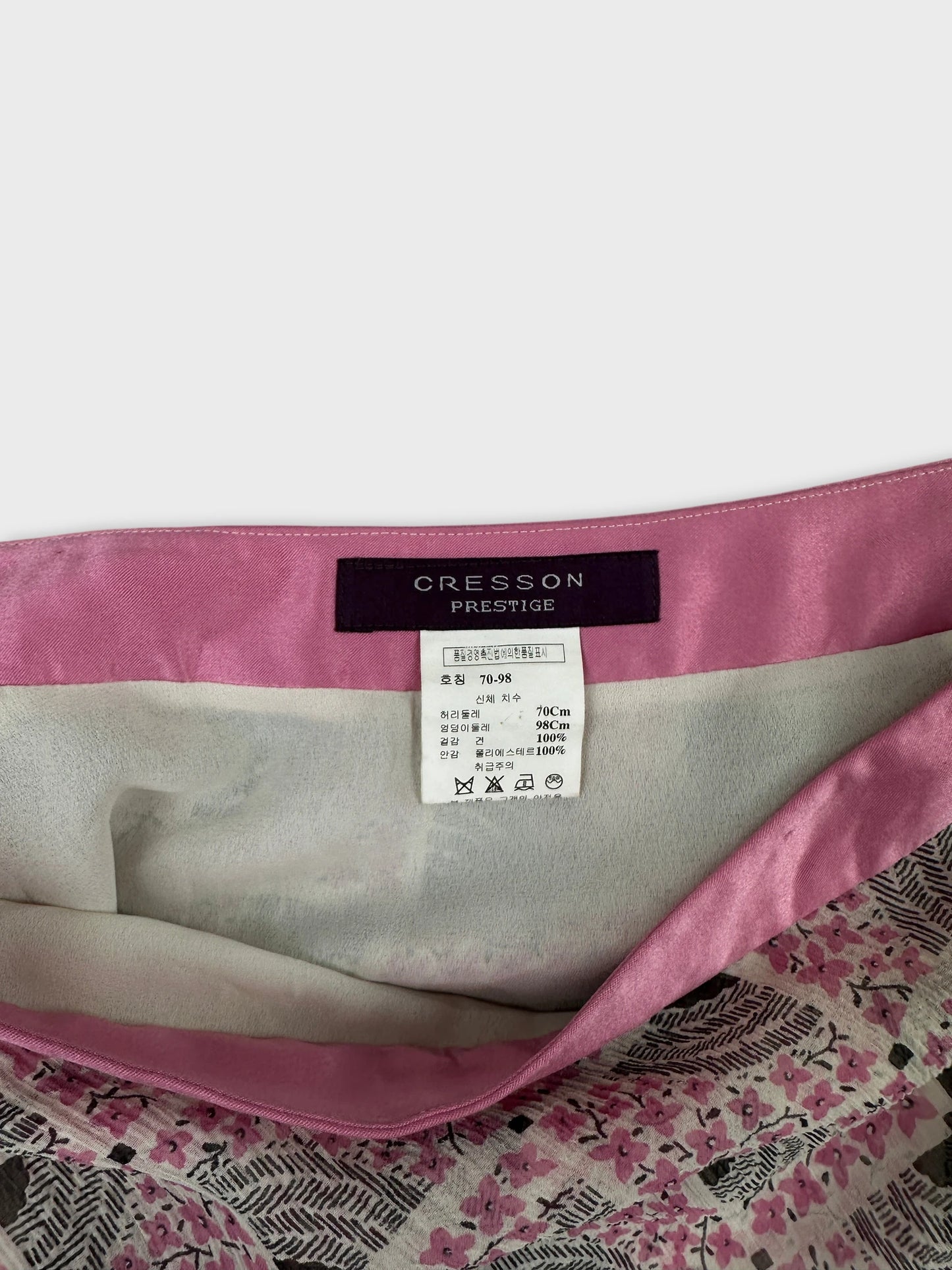 Detail view of a vintage women's skirt with a floral print and pink waistband.
