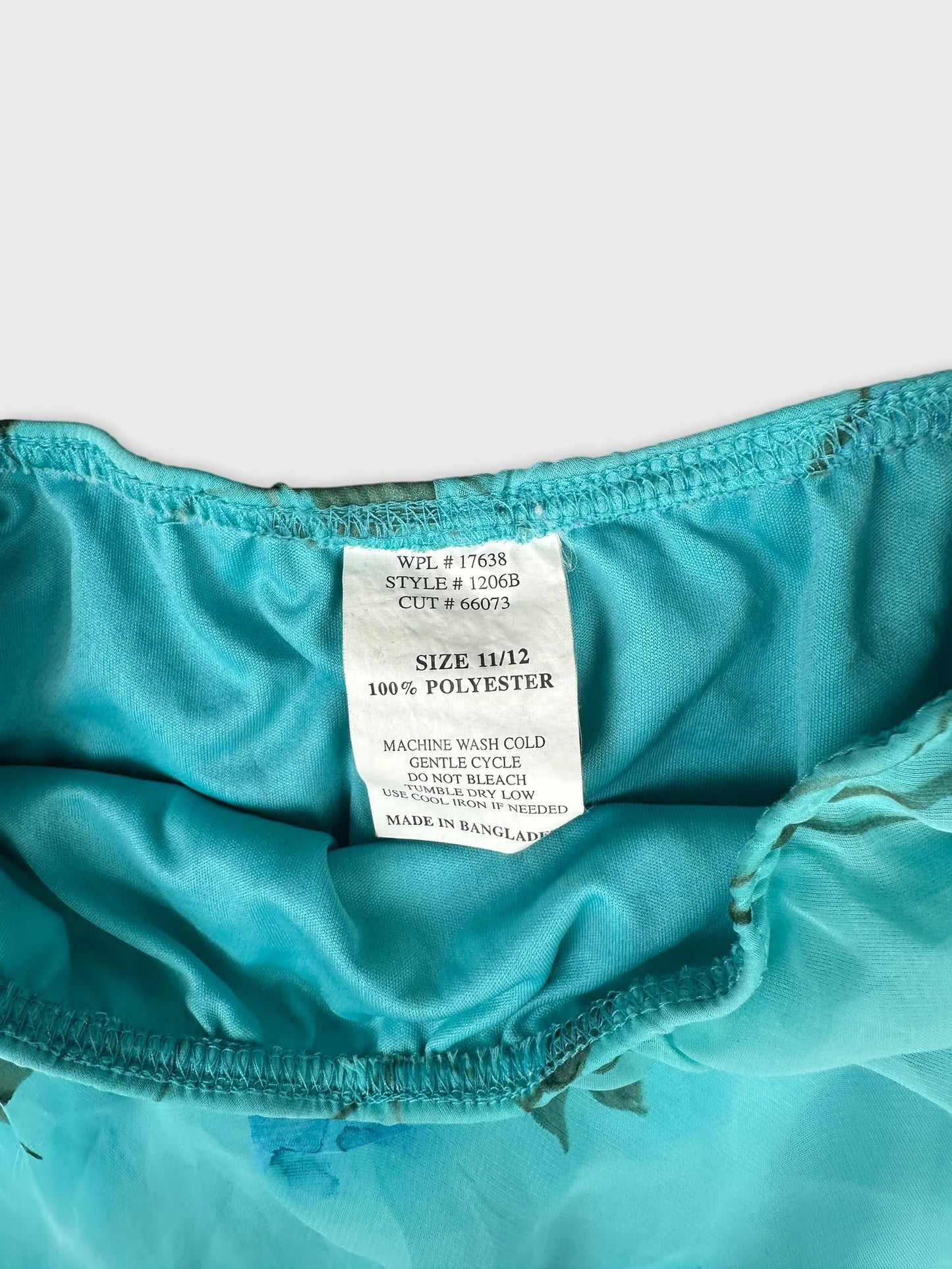 Detail view of a teal skirt with floral print and elastic waistband.