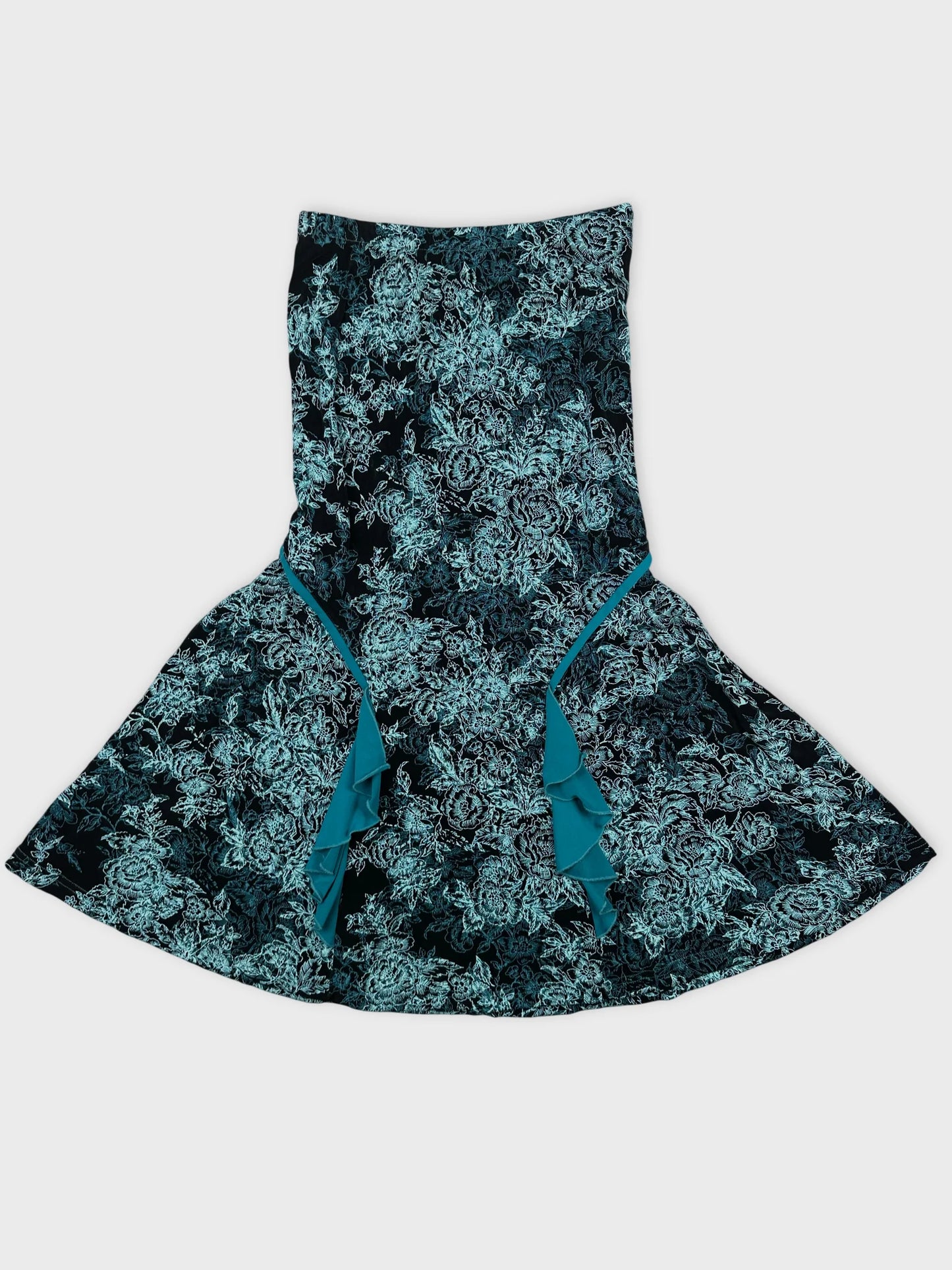Detail view of a flared black skirt with teal floral pattern and ruffle trim.