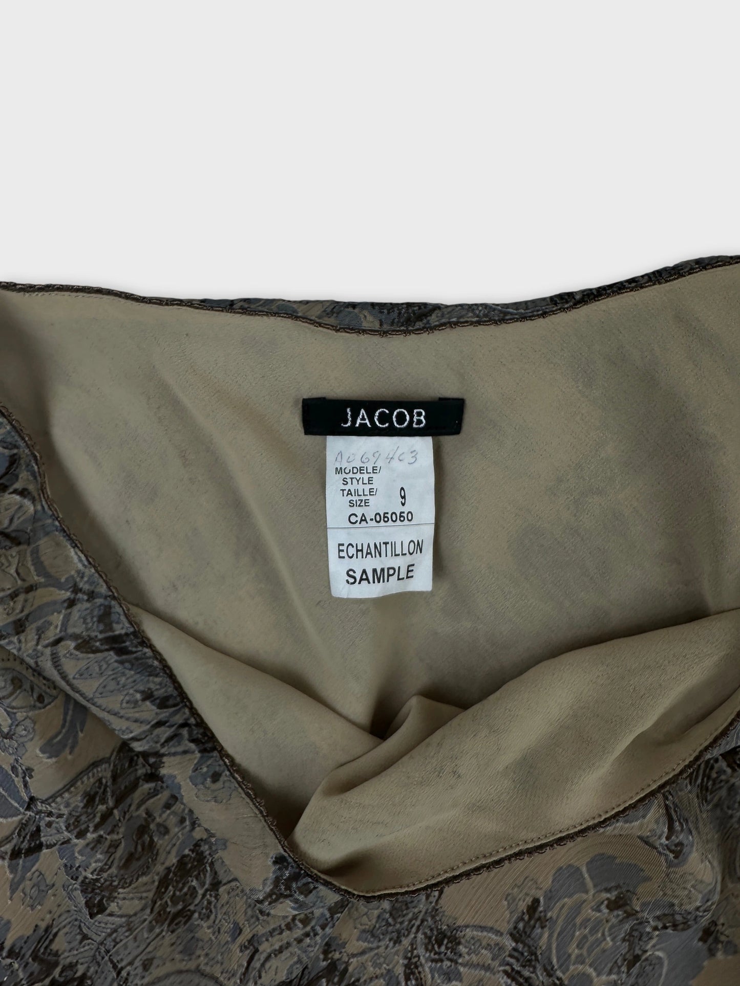 Detail view of a beige skirt with floral print and lace trim.