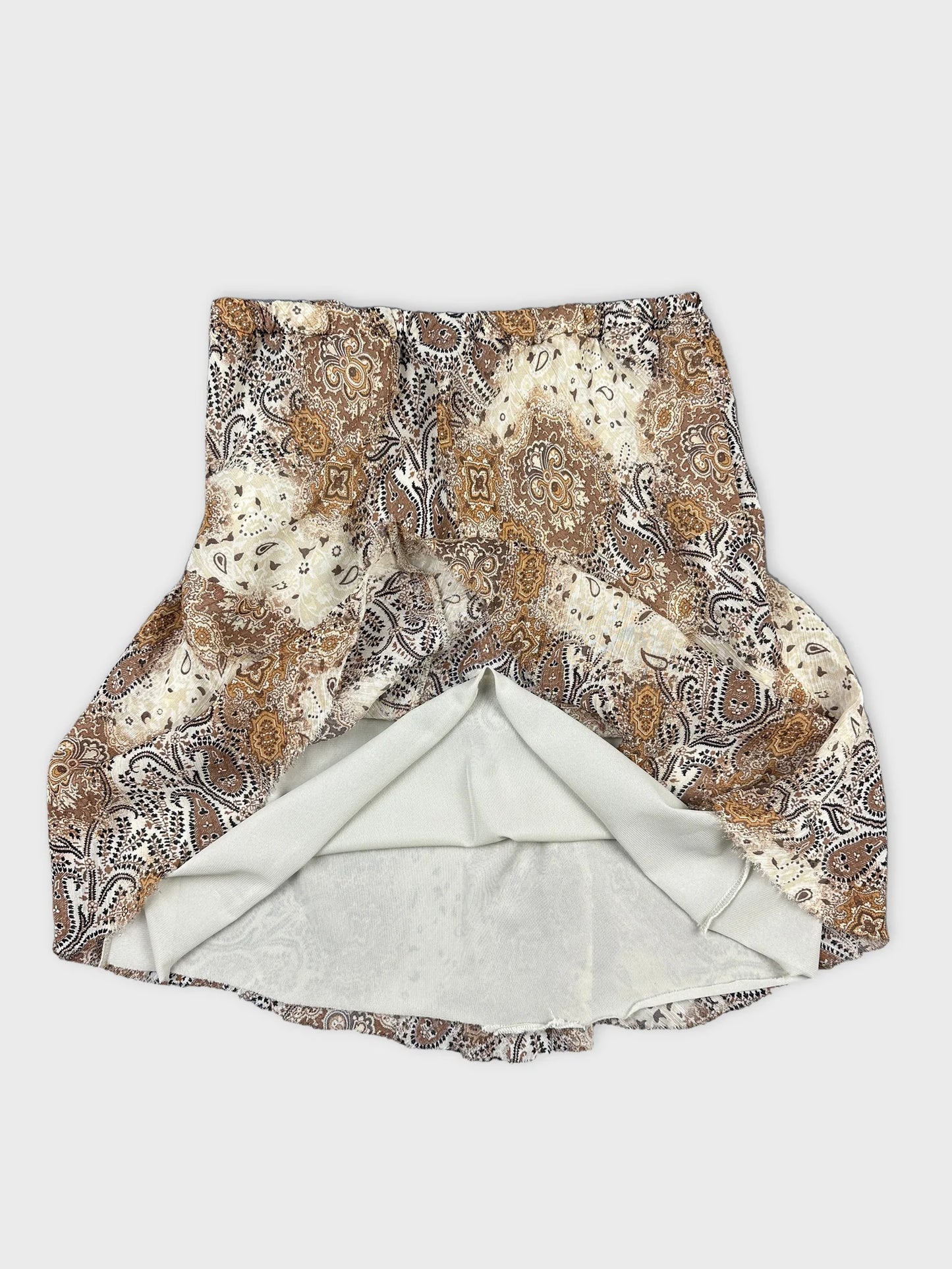 Detail view of a vintage women’s skirt featuring a paisley pattern in brown and cream.