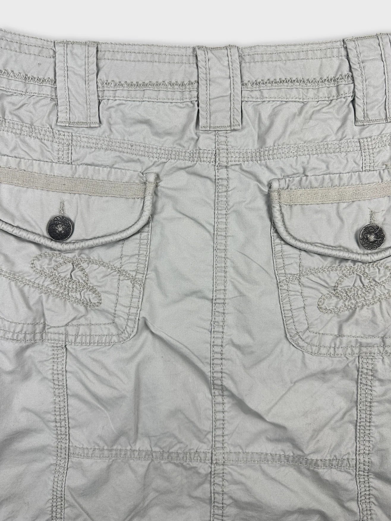 Detail view of a light gray skirt with embroidered pockets.