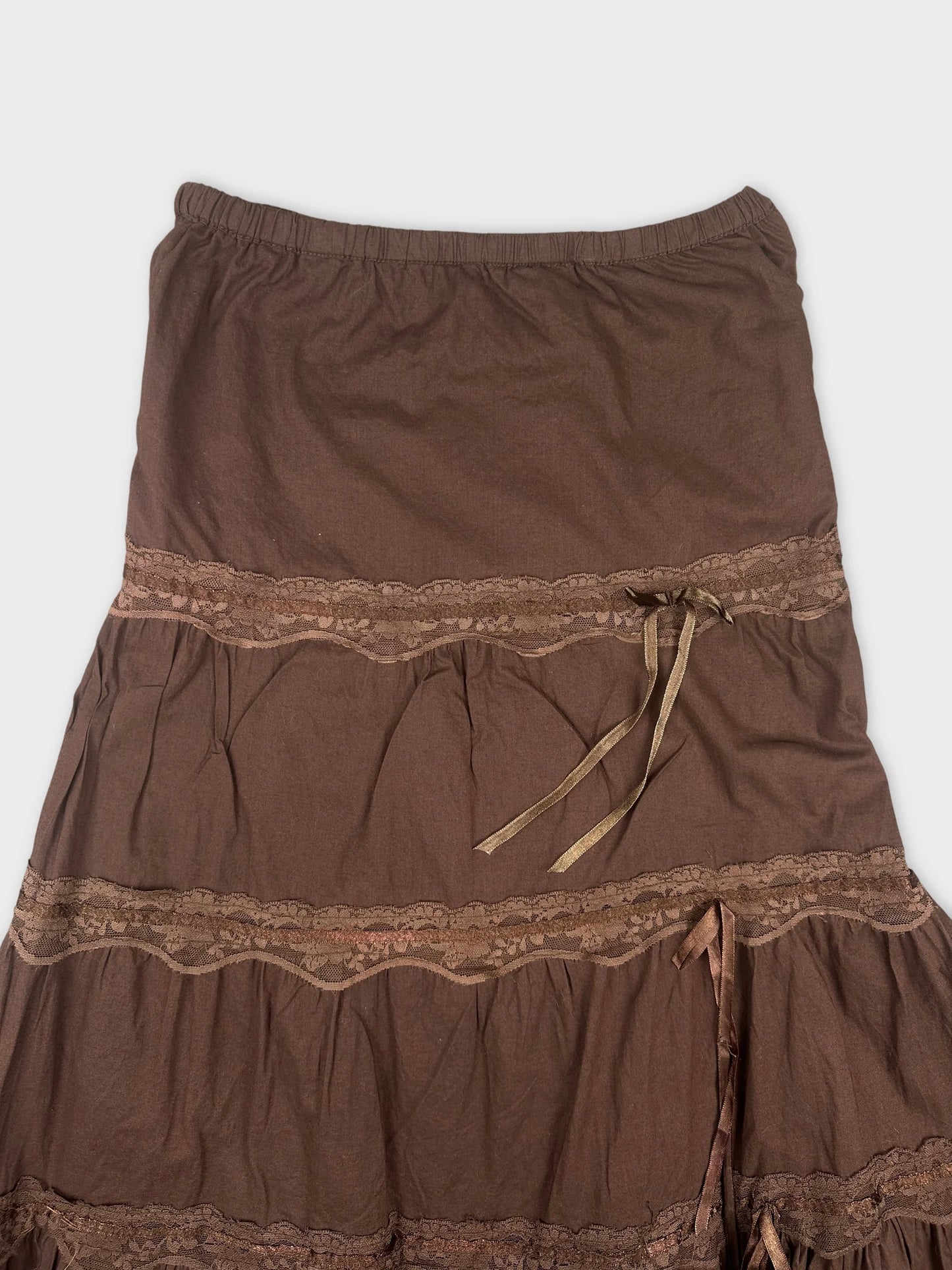 detail view of brown skirt featuring lace trim and ribbon accents