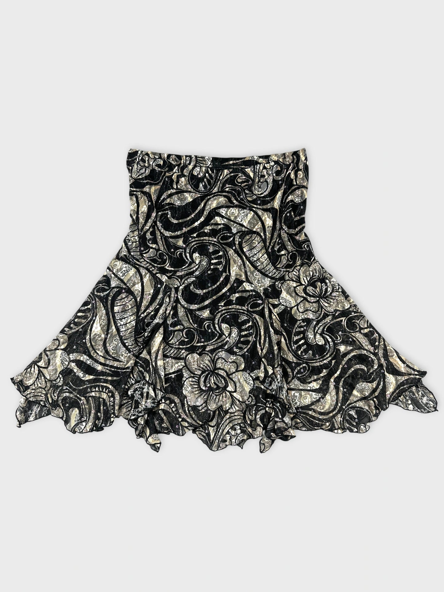 Front view of a black skirt with silver floral pattern and ruffled hem.
