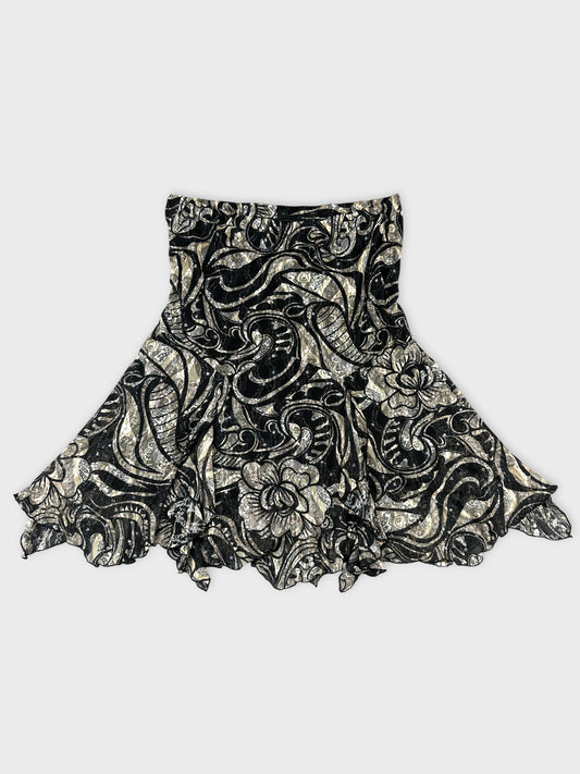 Front view of a black skirt with silver floral pattern and ruffled hem.