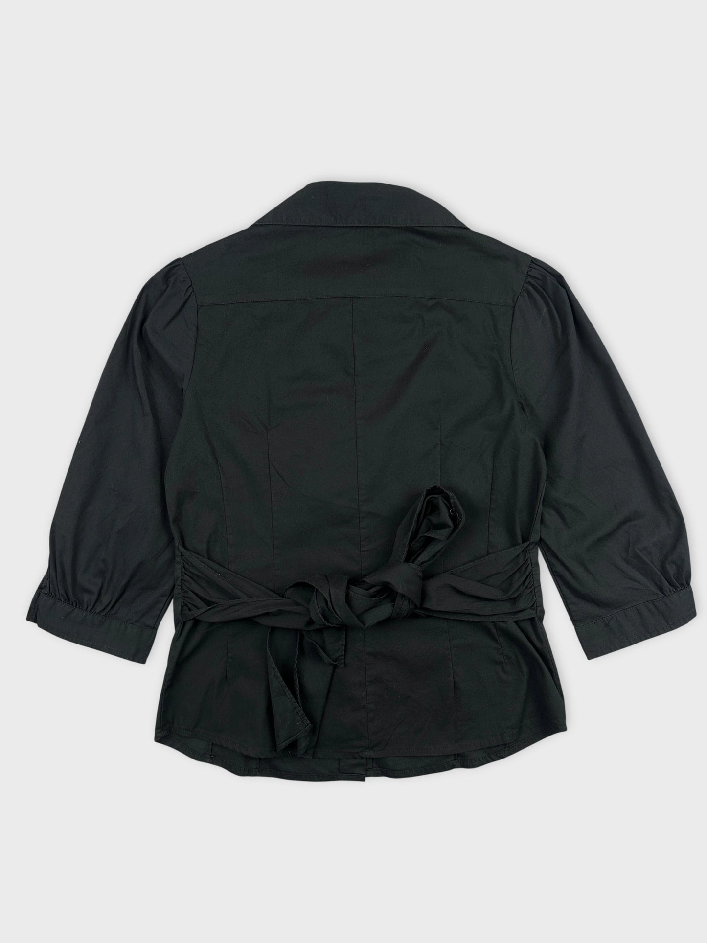 Back view of a black vintage women’s shirt with a tied waist detail.