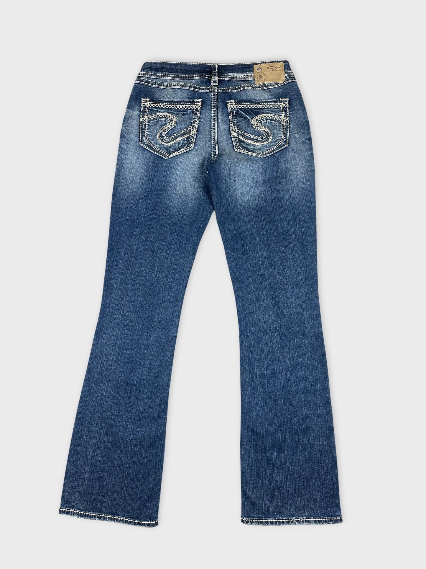 Back view of women denim jeans in dark blue with decorative stitching on pockets.