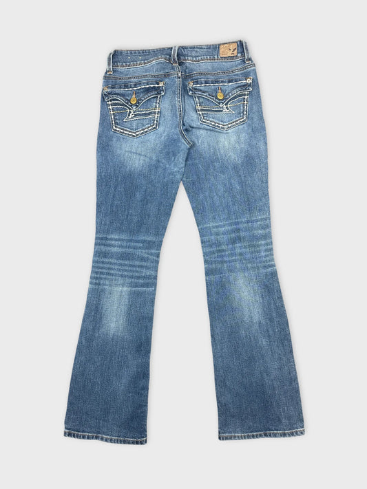 Back view of women denim jeans in faded blue with detailed pockets.