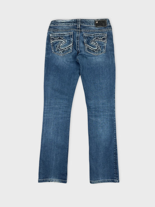 Back view of blue denim jeans with intricate pocket stitching detail.