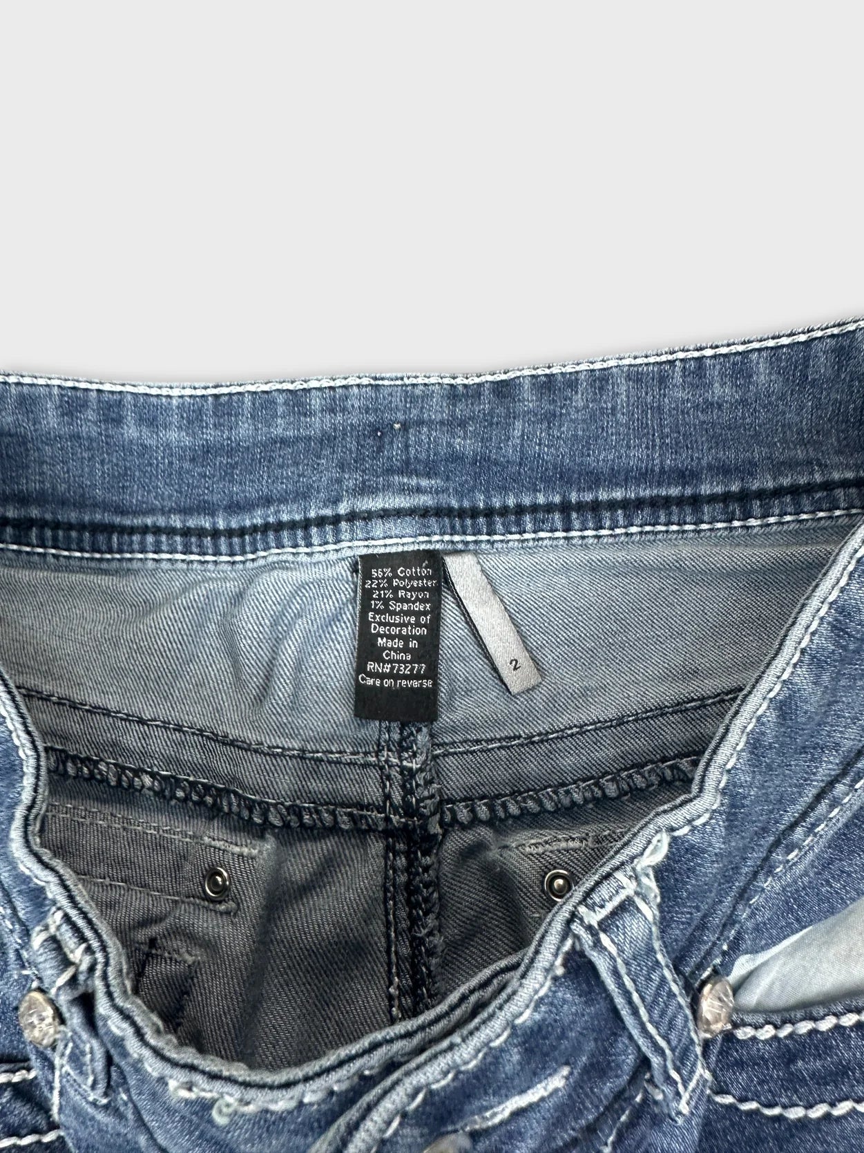 Detail view of women denim jeans showcasing the blue color and waistband stitching.