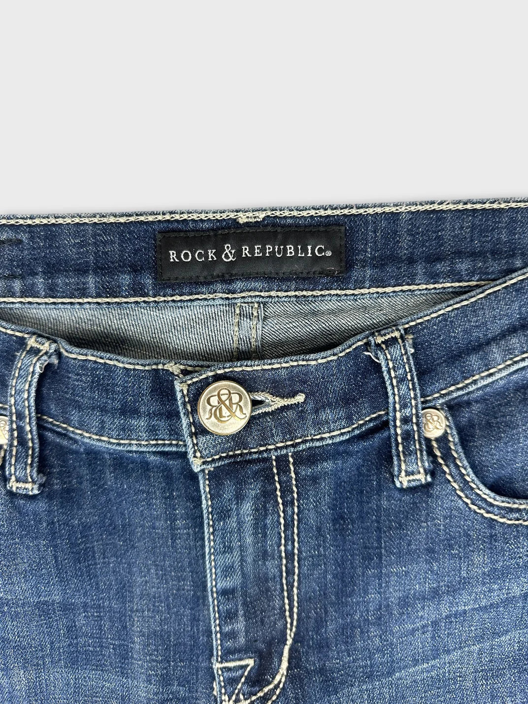 Detail view of women denim jeans in dark blue with metal buttons.