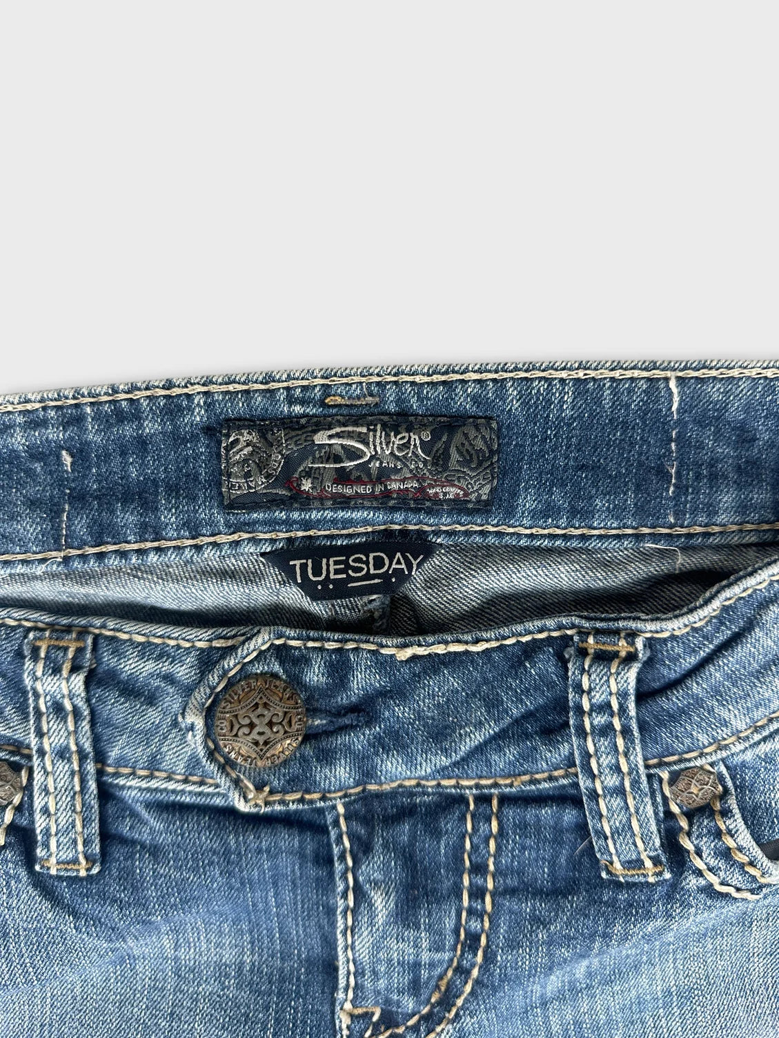 Detail view of women denim jeans in blue with decorative button.