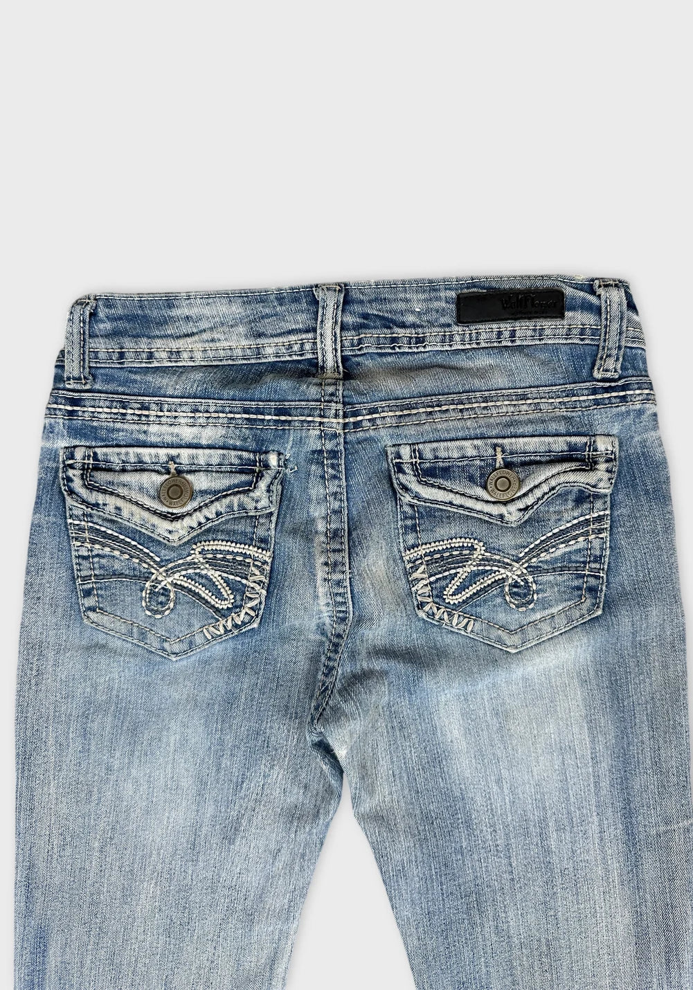 Detail view of women denim jeans featuring light blue color and decorative back pockets.