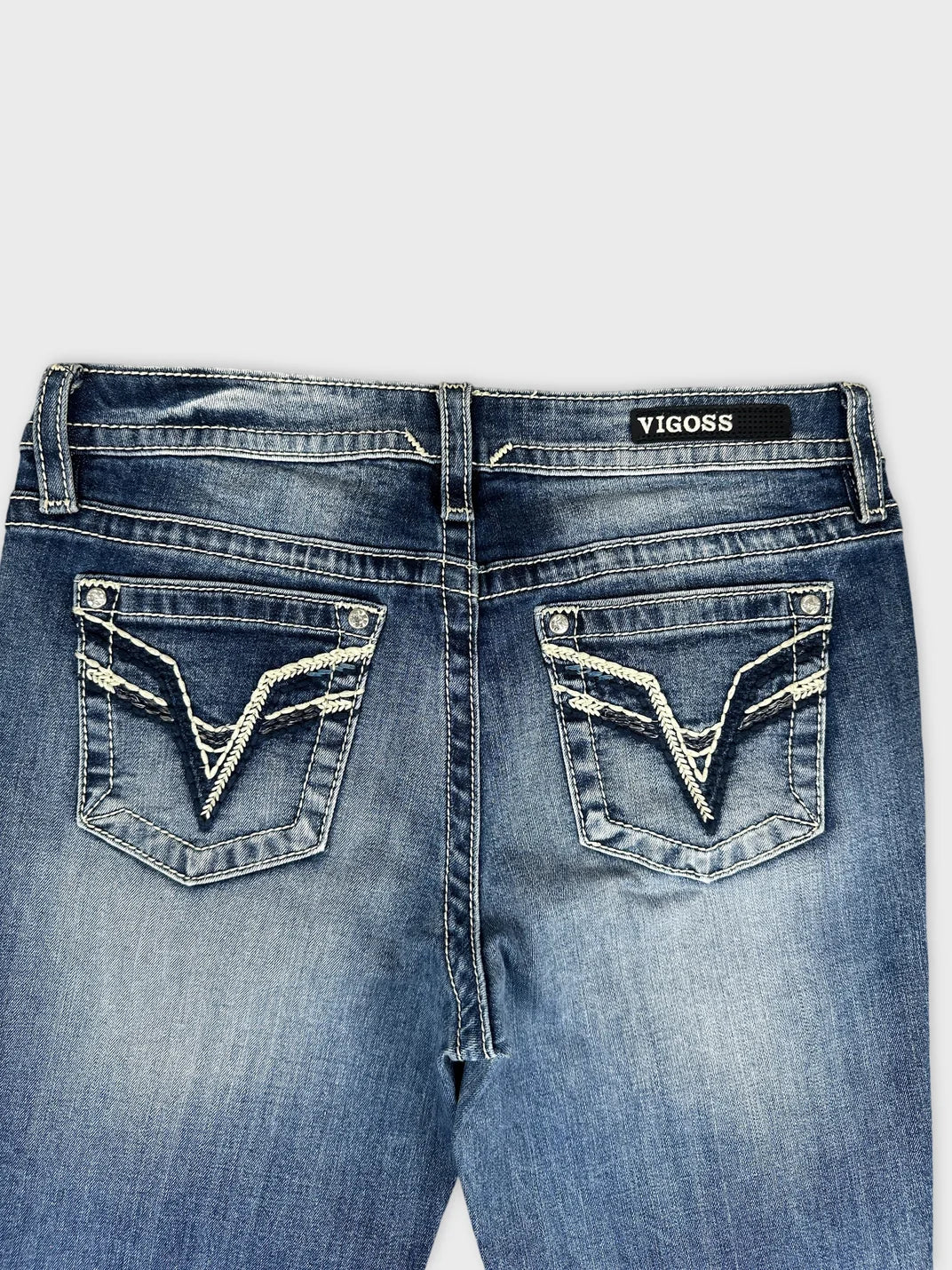 Detail view of women denim jeans in dark blue with distinctive stitching on pockets.