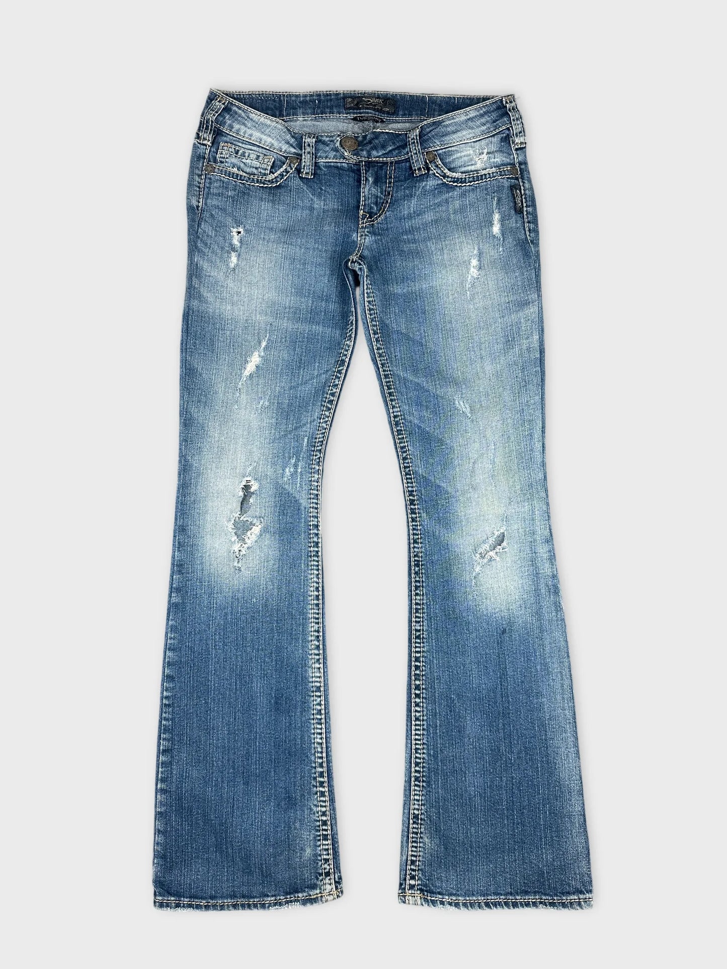Front view of blue denim jeans featuring distressed details and flared legs.