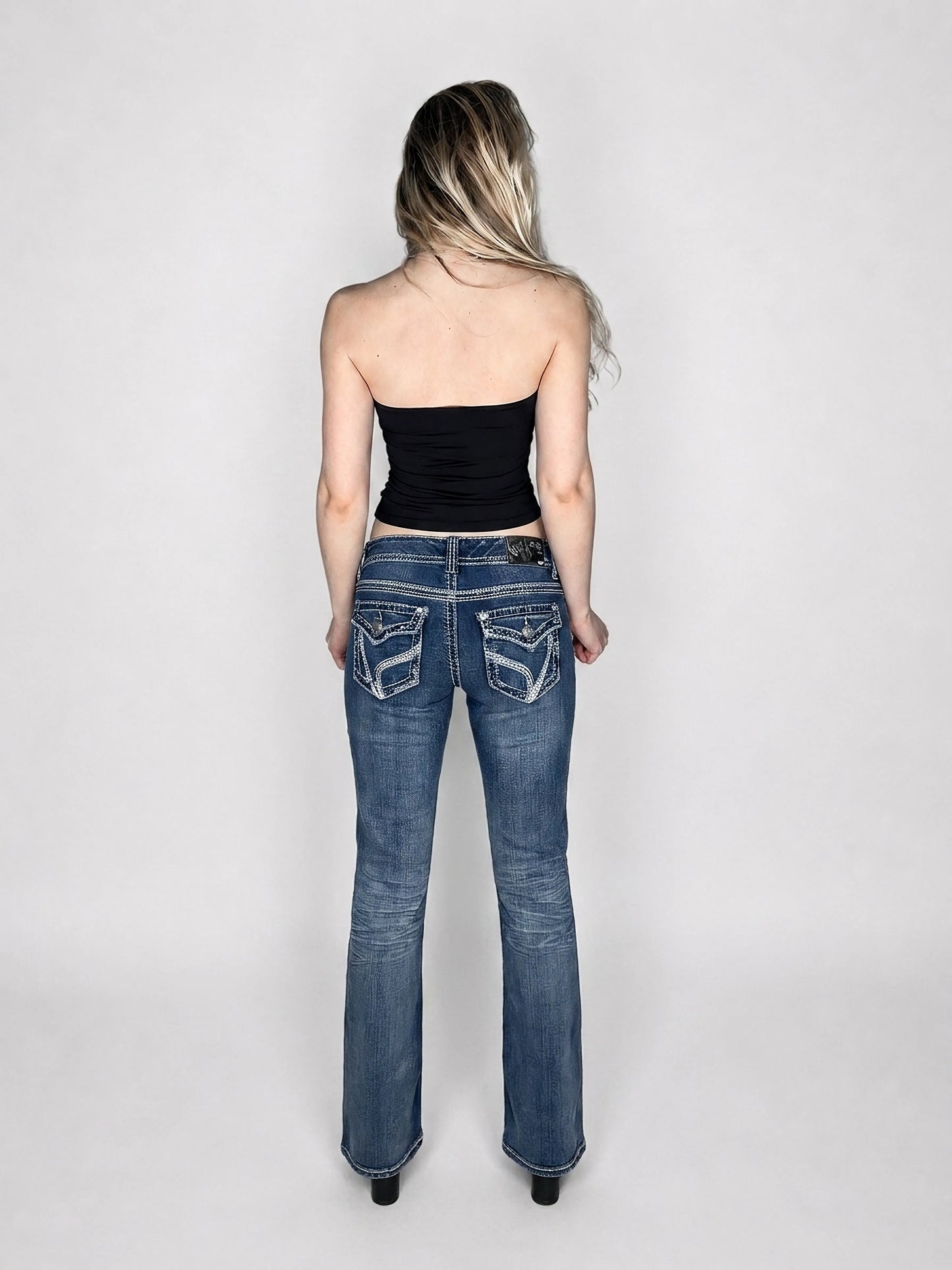 Back view of women denim jeans in blue with detailed pockets.