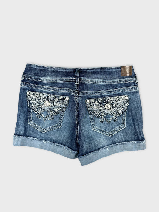 Back view of blue denim shorts featuring embroidered pocket details.