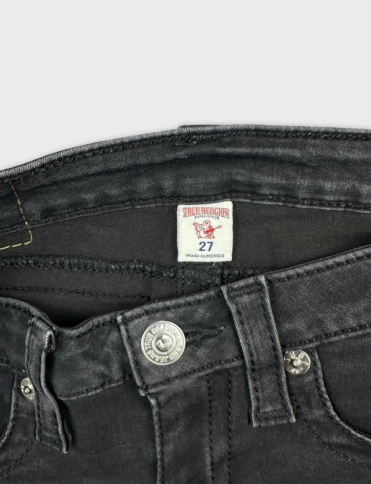 Detail view of black denim shorts highlighting button and stitching.