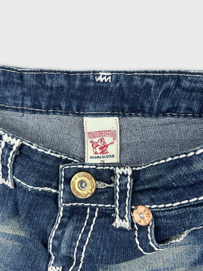 Detail view of women denim shorts featuring a gold button and tag.
