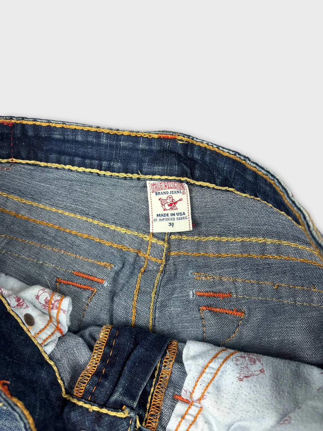 Detail view of women's denim shorts in blue featuring orange stitching.