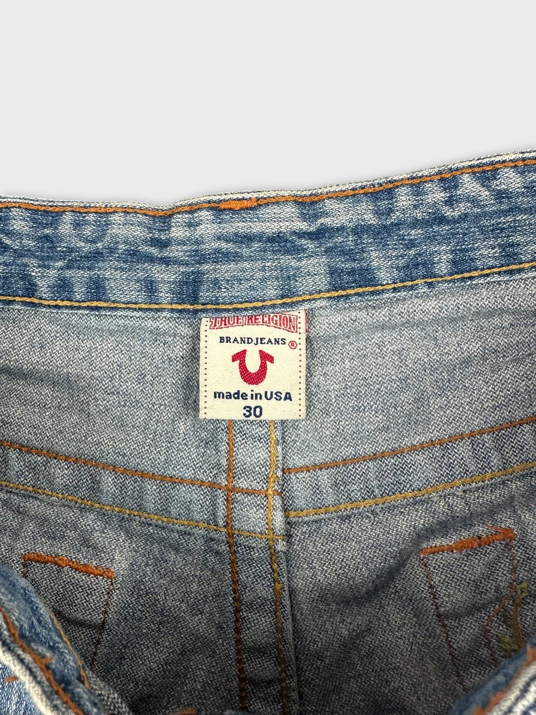 detail view of blue denim shorts showcasing stitching and waistband label