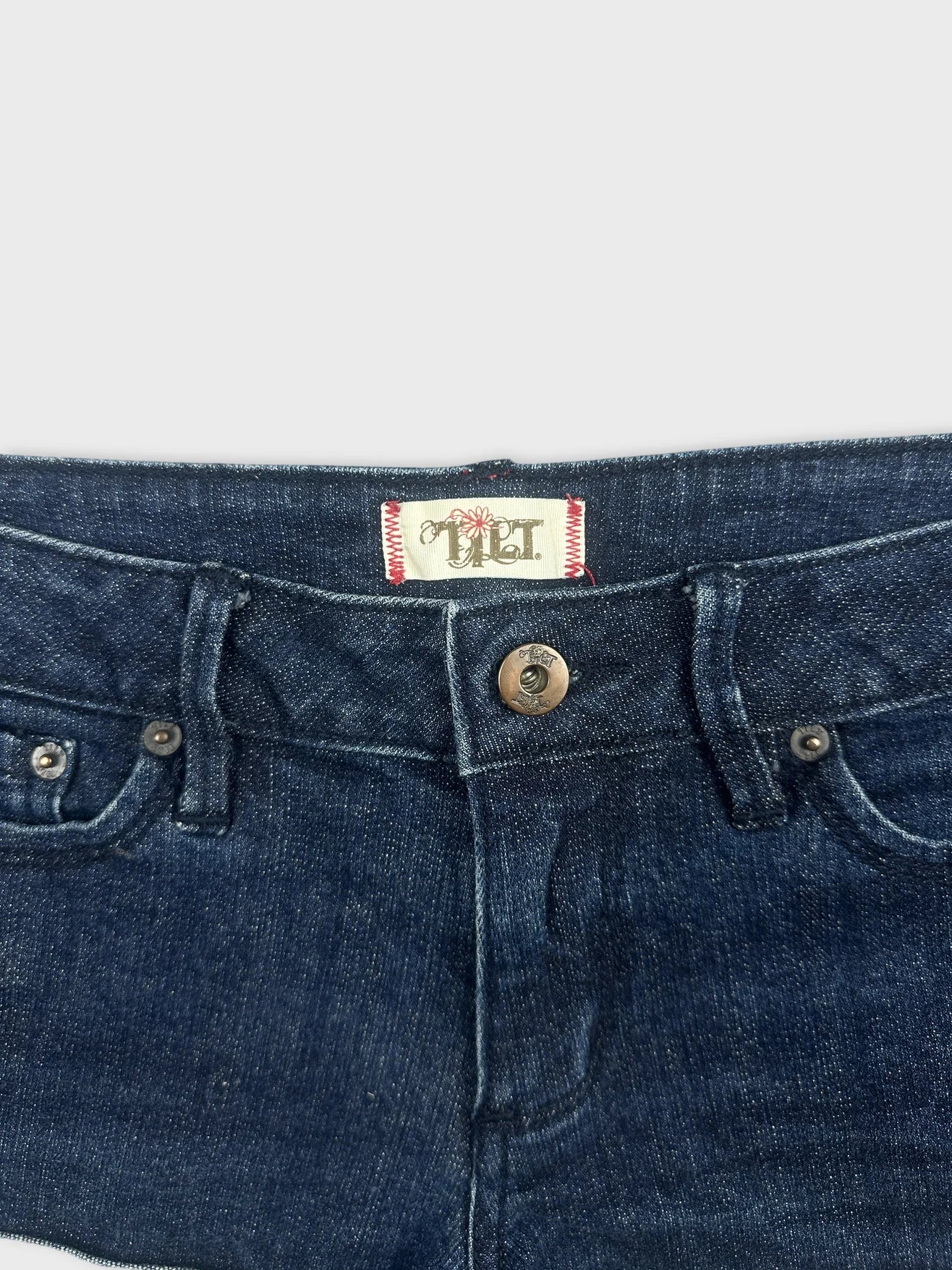 Detail view of women's denim shorts in dark blue with button closure.