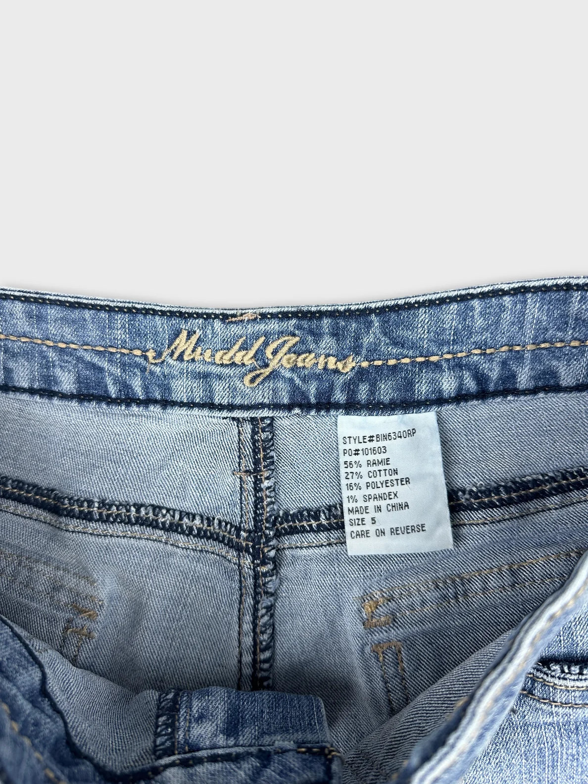 Detail view of women denim shorts featuring light blue fabric and embroidered brand name.